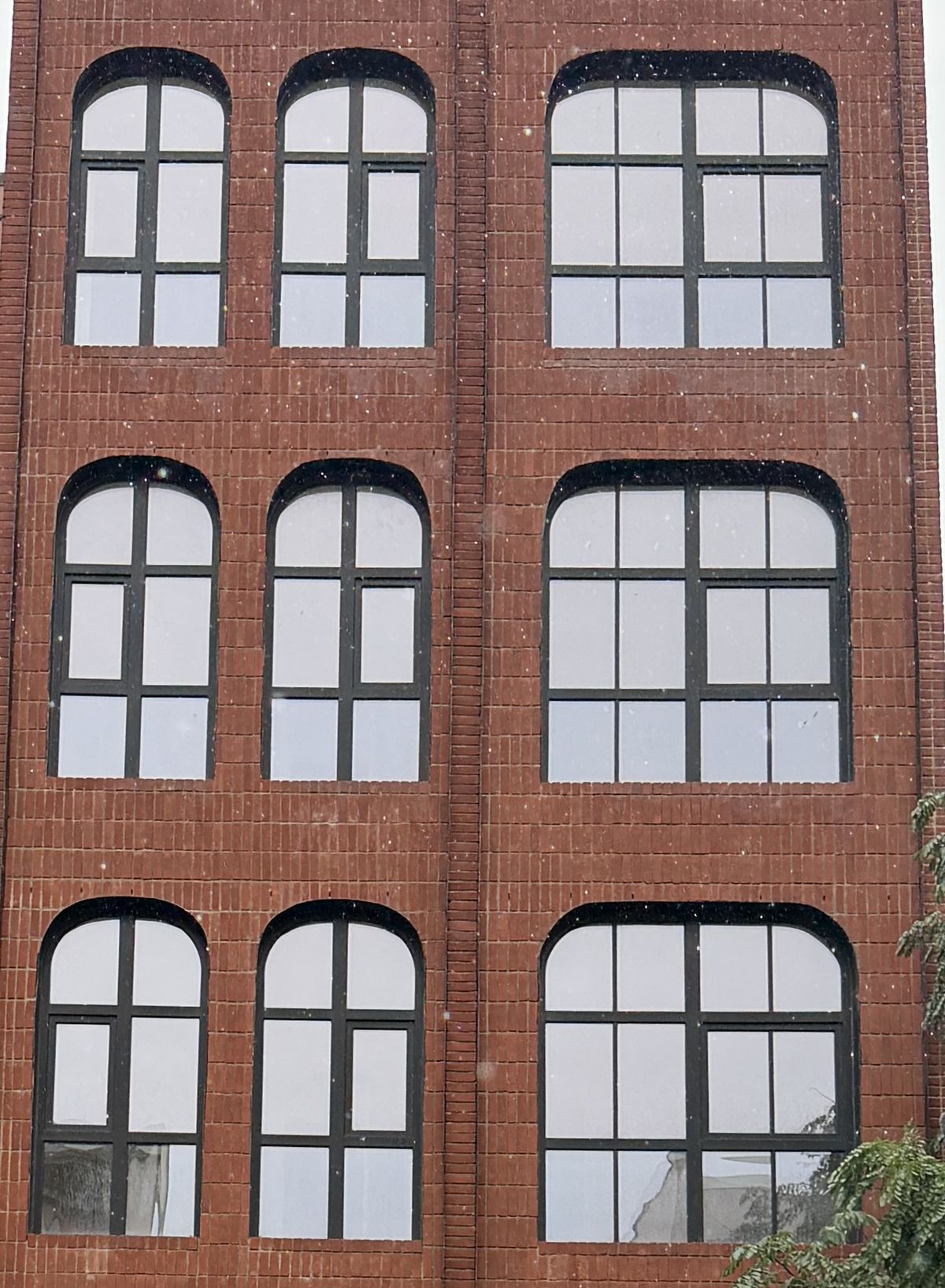 Three rows of radius-headed black windows in a flush red-brick bay